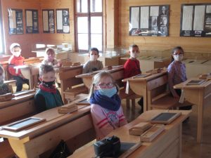 dzieci siedzą w starej szkole w drewnianych ławkach, na ławkach drewniane kałamarze, tabliczki 