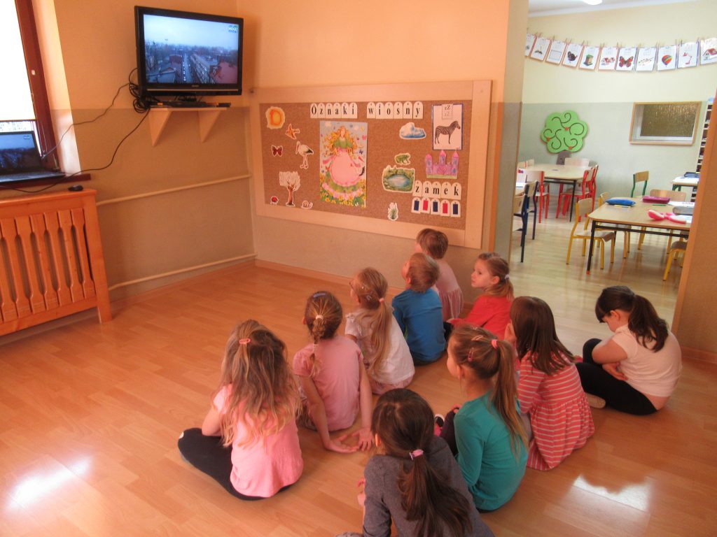 Dzieci siedzą przed telewizorem i oglądają film.