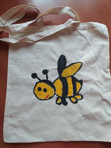 Biała torba materiałowa na której namalowana jest farbami pszczółka