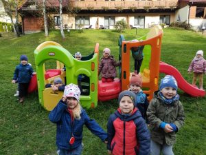 Dzieci stoją na placu zabaw przed plastikowym pociągiem.