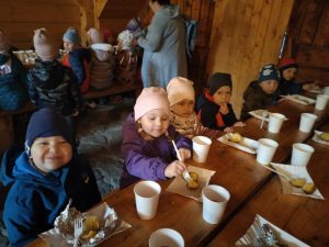 Dzieci siedzi za stołem i je ziemniaki.