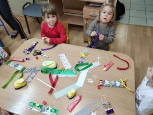 Dzieci siedzą za stołami wykonują zakładkę do książki