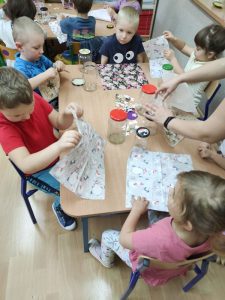Dzieci ozdabiają serwetką nakrętki od słoika
