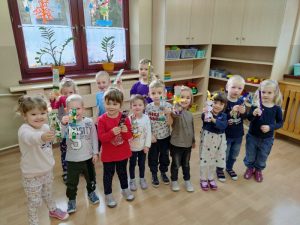 Dzieci stoją w półkolu, każde z nich trzyma w ręce przed sobą zakładkę do książki. 