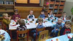 Dzieci siedzą przy stolikach nakrytych białymi obrusami.