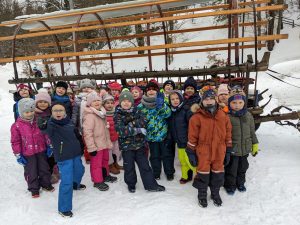 grupa średniaków pozuje do zdjęcia przed wozem,