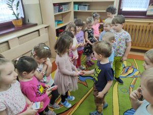 Chłopcy wręczają słodki upominek dziewczynkom z grupy.