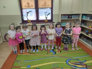 Dziewczynki stoją na środku sali, trzymają w ręce cukierki.