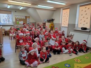 Dzieci siedzą na dywanie w oczekiwaniu na Mikołaja.
