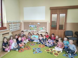 Dzieci siedzą pod tablicą z sylwetą Wróbelka Elemelka 