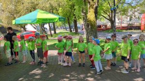 dzieci w zielonych koszulkach stoją w kolejce i czekają na lody