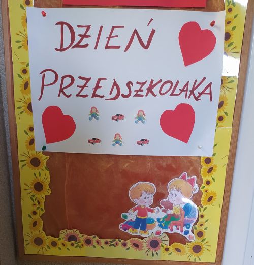 napis na tablicy "Dzień Przedszkolaka" pod spodem na obrazku dzieci i serduszka