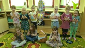 dziewczynki z grupy stoją w szeregu, prezentują niespodzianki kwiatki, lizaki, ciastka, w srodku balon w kształcie motylka i koszyk