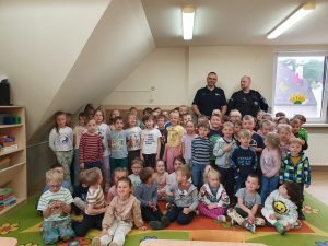 Przedszkolaki pozują do zdjęcia z policjantami.
