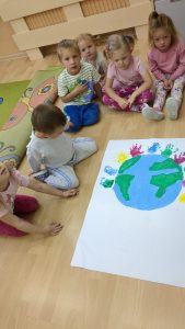 Dzieci siedź dookoła pomalowanej przez nie ziemi.