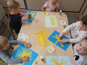 Dzieci robią słońce z papieru kolorowego, naklejają żółte słońce, wycinają promyki,