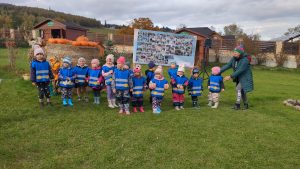 Grupa maluchów pozuje na tle banera, na którym są zdjęcia z zajęć oraz symbole projektu 