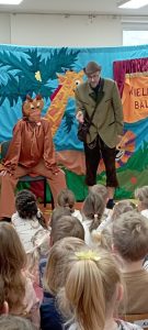 Aktórzy w postaciach wiewiórki i myśliwego na tle lasu na banerze.