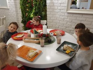 Dzieci siedzą przy stoliku i jedzą naleśniki.