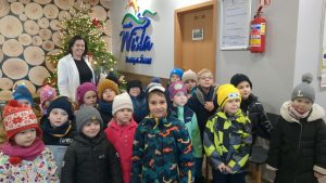 Dzieci z grupy średniaków i starszakow pozują do zdjęcia z Panią   burmistrz miasta. W tle choinka i logo Wisły.