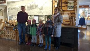 Na zdjęciu czworo dzieci, kierownik muzeum. W tle wystawa z muzeum.